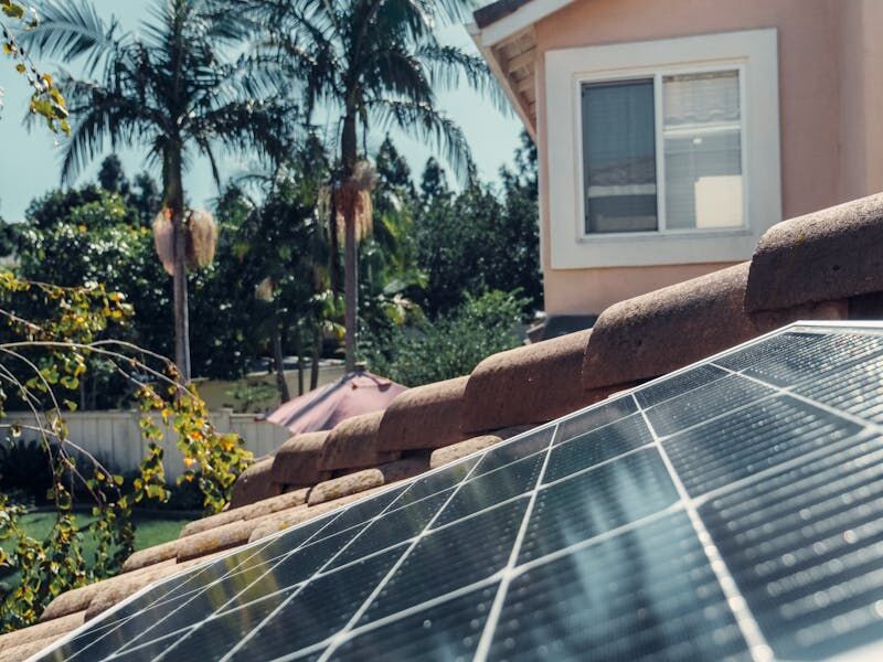 Solar panels on the tiled roof of a house, with palm trees behind